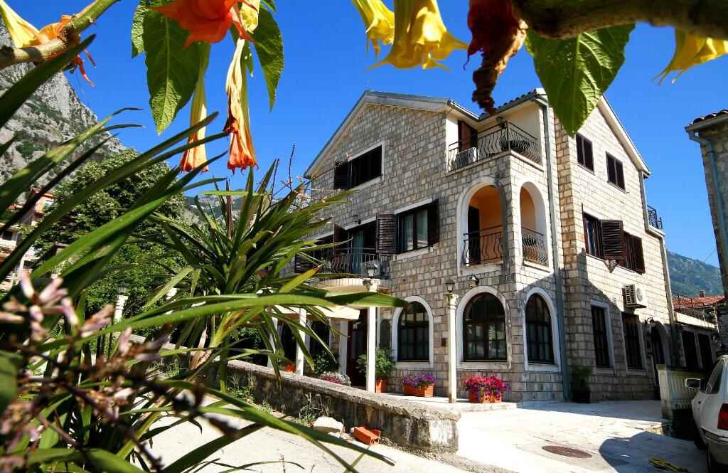 Stone facade of Vila Panonija with flowers and mountains behind
